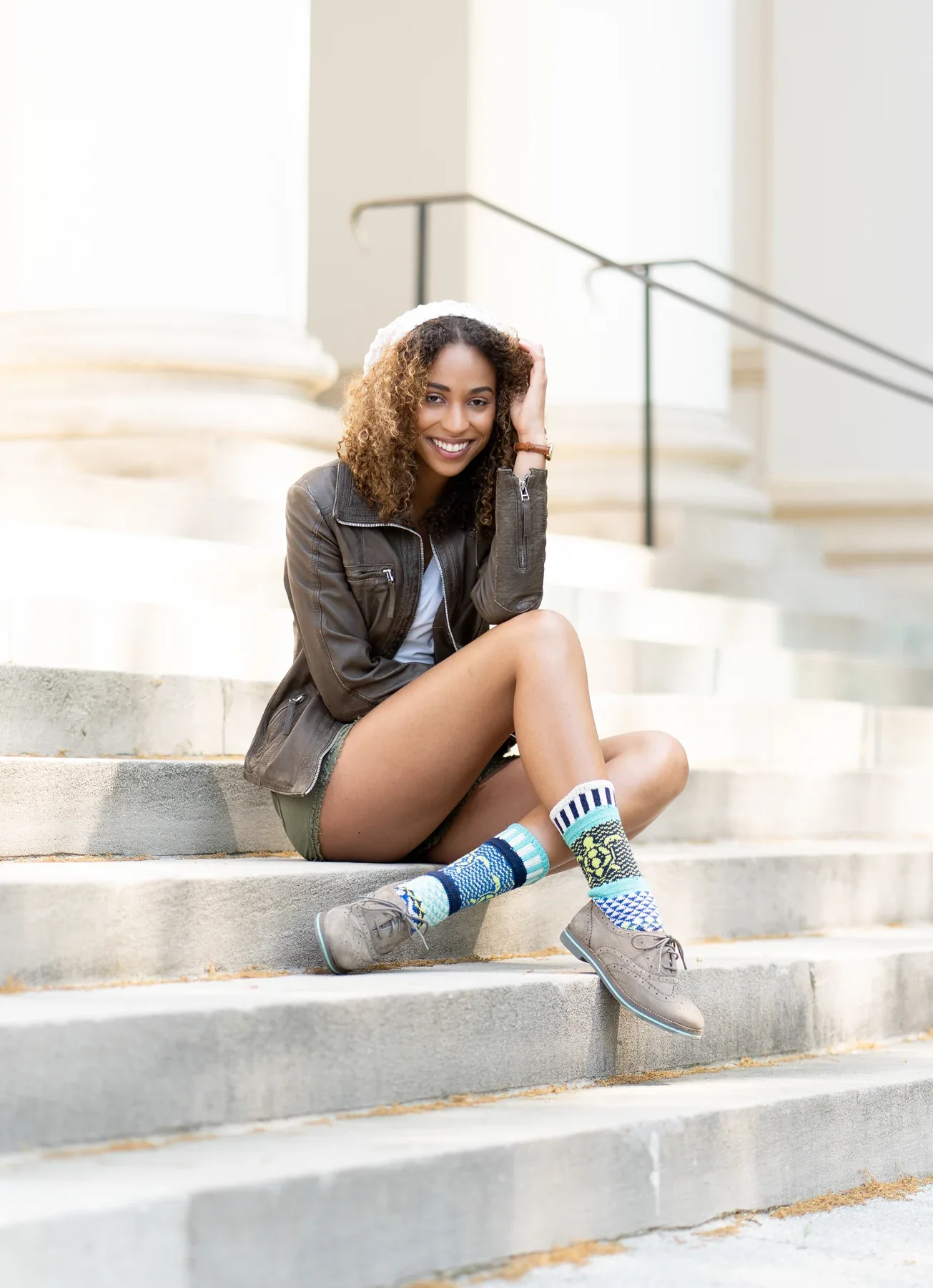 Colorful socks styled with sneakers, shorts, and a jacket on stone steps.